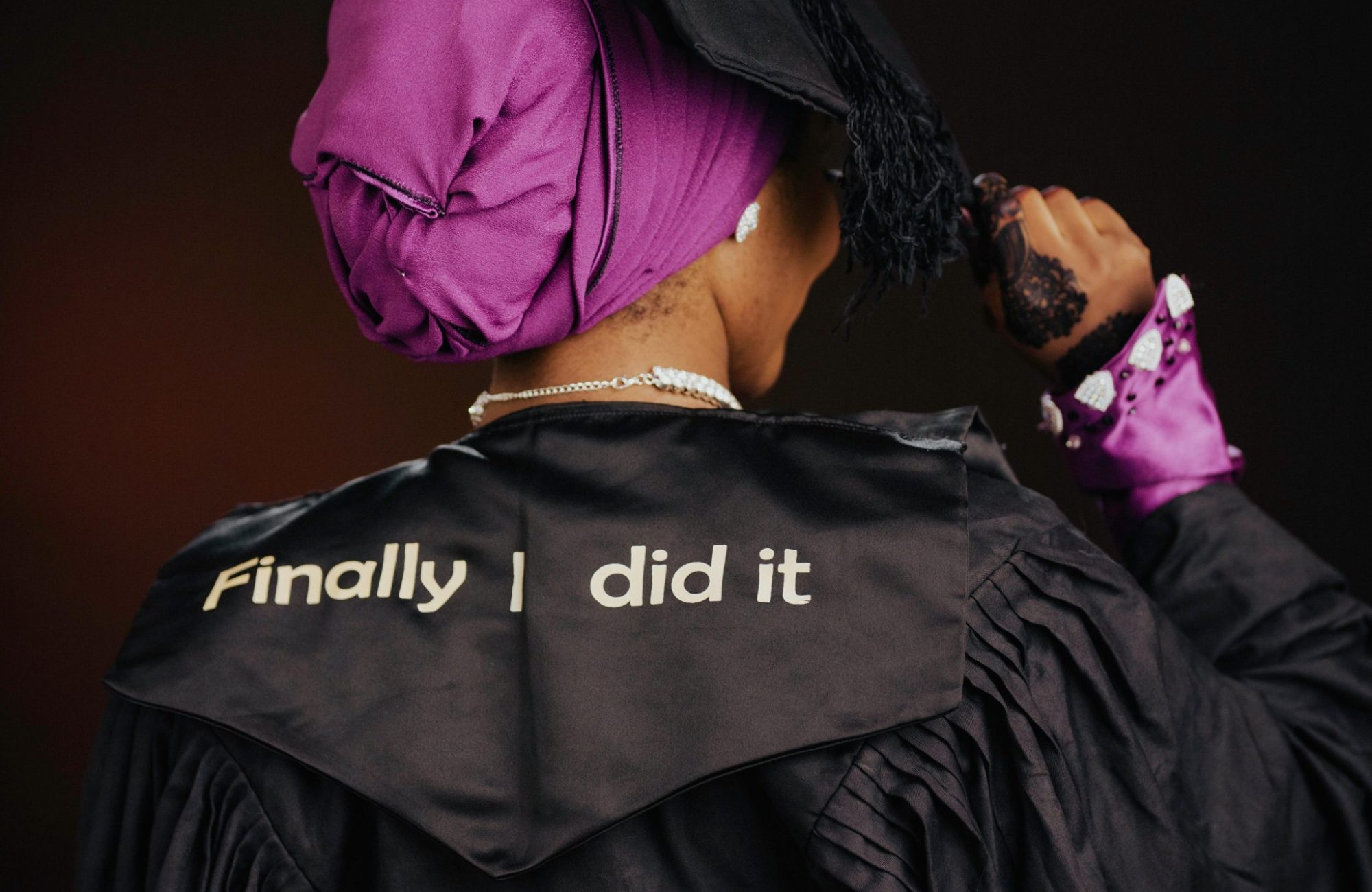 Back view of a female graduate in cap and gown celebrating her success with a message.